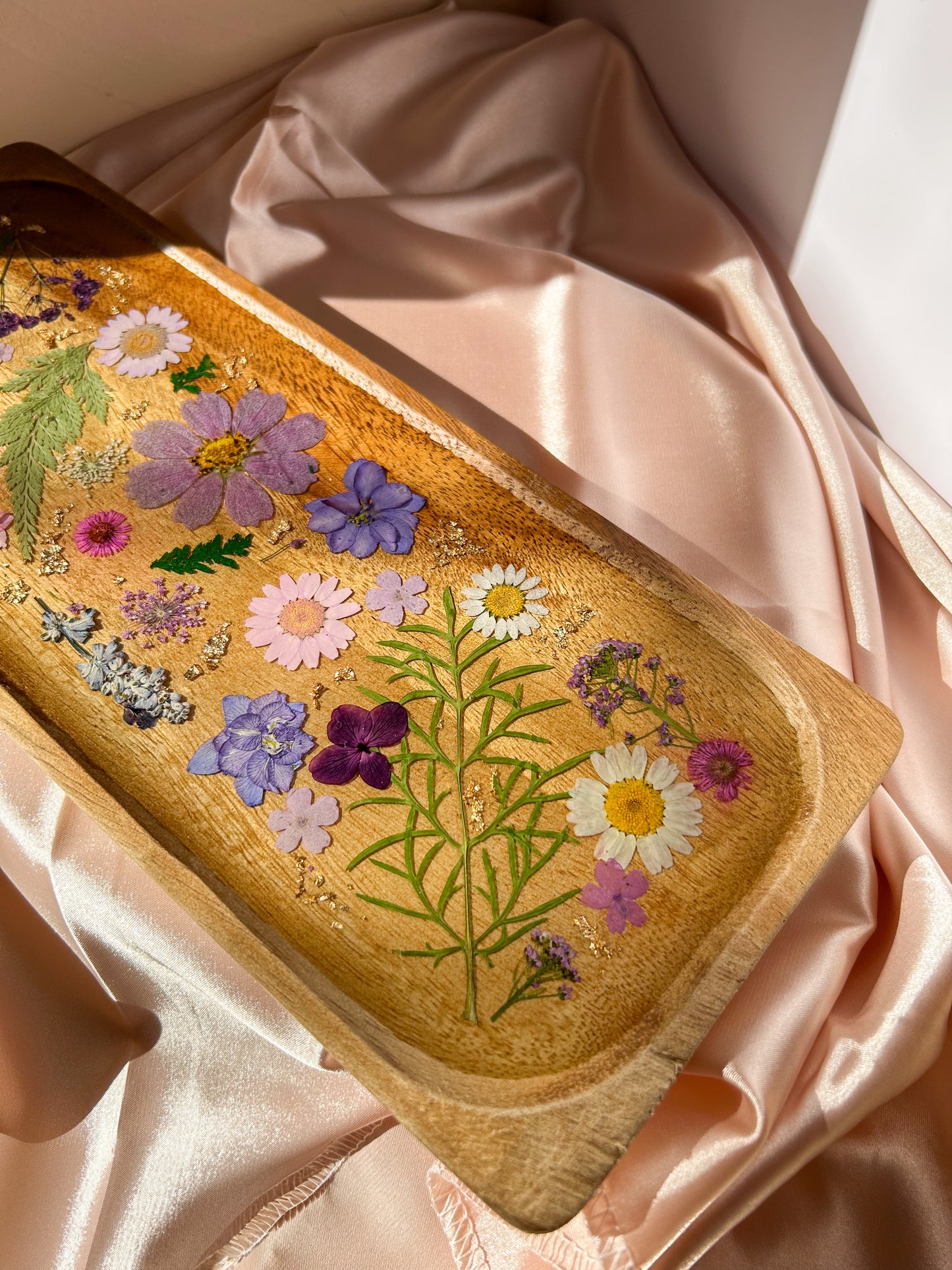 A beautiful decorative wood and resin tray with real natural dried flowers in a colorful pink, purple, green, white, yellow, and blue arrangement. size is 35 cm × 14 cm, approximately 13.78 inches × 5.51 inches. It is a beautiful thoughtful gift for a loved one and decorates every space effortlessly.