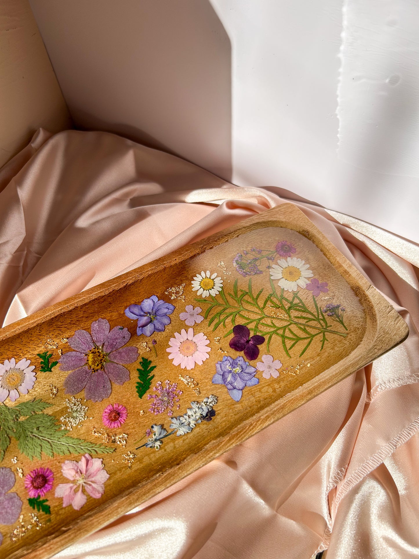 A beautiful decorative wood and resin tray with real natural dried flowers in a colorful pink, purple, green, white, yellow, and blue arrangement. size is 35 cm × 14 cm, approximately 13.78 inches × 5.51 inches. It is a beautiful thoughtful gift for a loved one and decorates every space effortlessly.