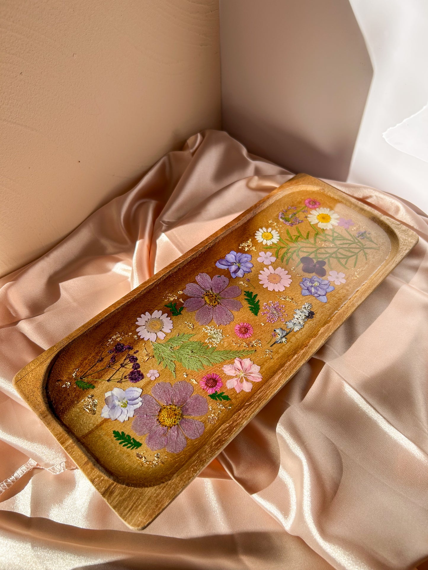 A beautiful decorative wood and resin tray with real natural dried flowers in a colorful pink, purple, green, white, yellow, and blue arrangement. size is 35 cm × 14 cm, approximately 13.78 inches × 5.51 inches. It is a beautiful thoughtful gift for a loved one and decorates every space effortlessly.