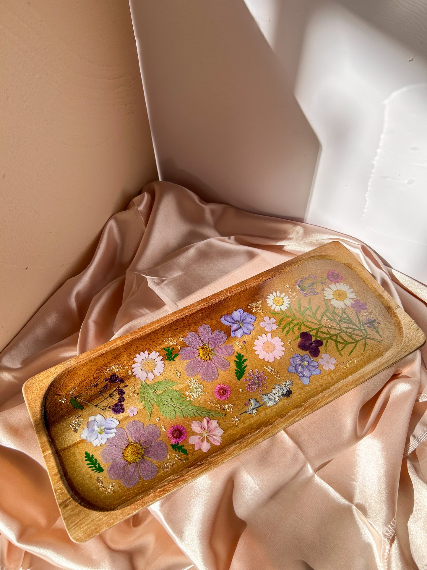 A beautiful decorative wood and resin tray with real natural dried flowers in a colorful pink, purple, green, white, yellow, and blue arrangement. size is 35 cm × 14 cm, approximately 13.78 inches × 5.51 inches. It is a beautiful thoughtful gift for a loved one and decorates every space effortlessly.