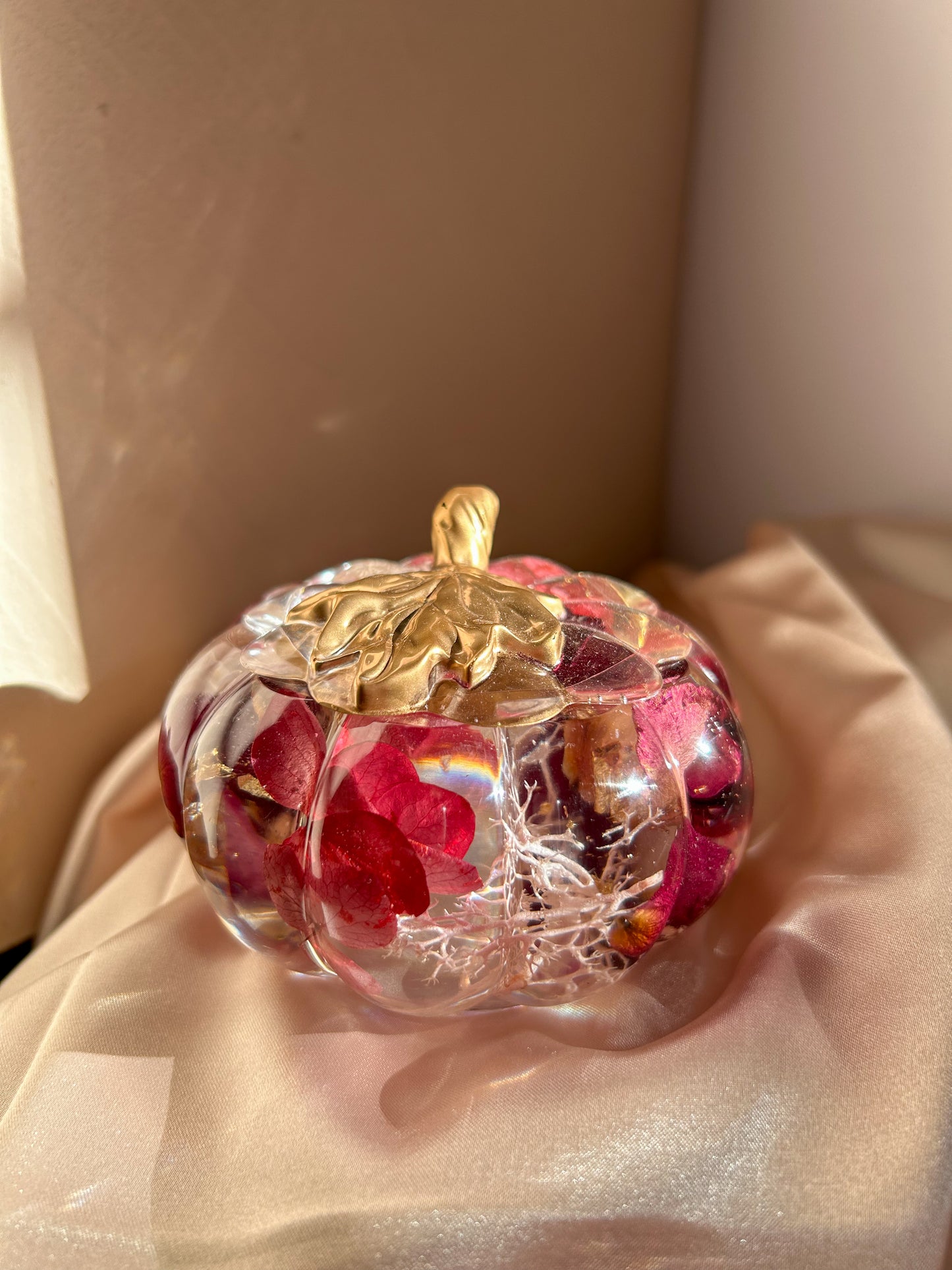 A handmade floral pumpkin-shaped resin jewelry jar with real dried flowers embedded inside. The jar has a smooth, glossy finish and is designed for storing rings, earrings, necklaces, and other small jewelry. Its elegant nature-inspired design makes it a unique decorative piece, perfect for boho or cottagecore home decor.