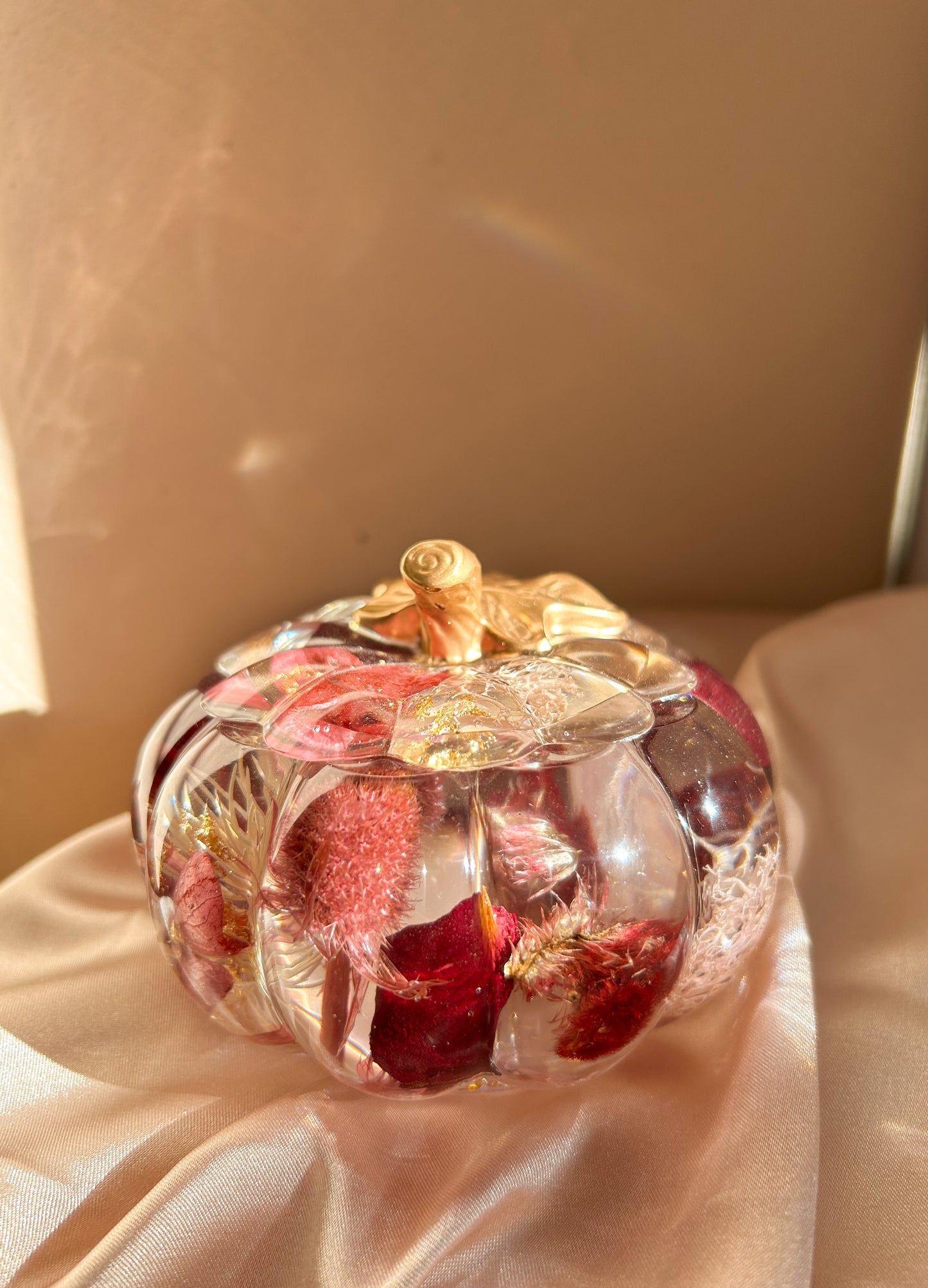 A handmade floral pumpkin-shaped resin jewelry jar with real dried flowers embedded inside. The jar has a smooth, glossy finish and is designed for storing rings, earrings, necklaces, and other small jewelry. Its elegant nature-inspired design makes it a unique decorative piece, perfect for boho or cottagecore home decor.