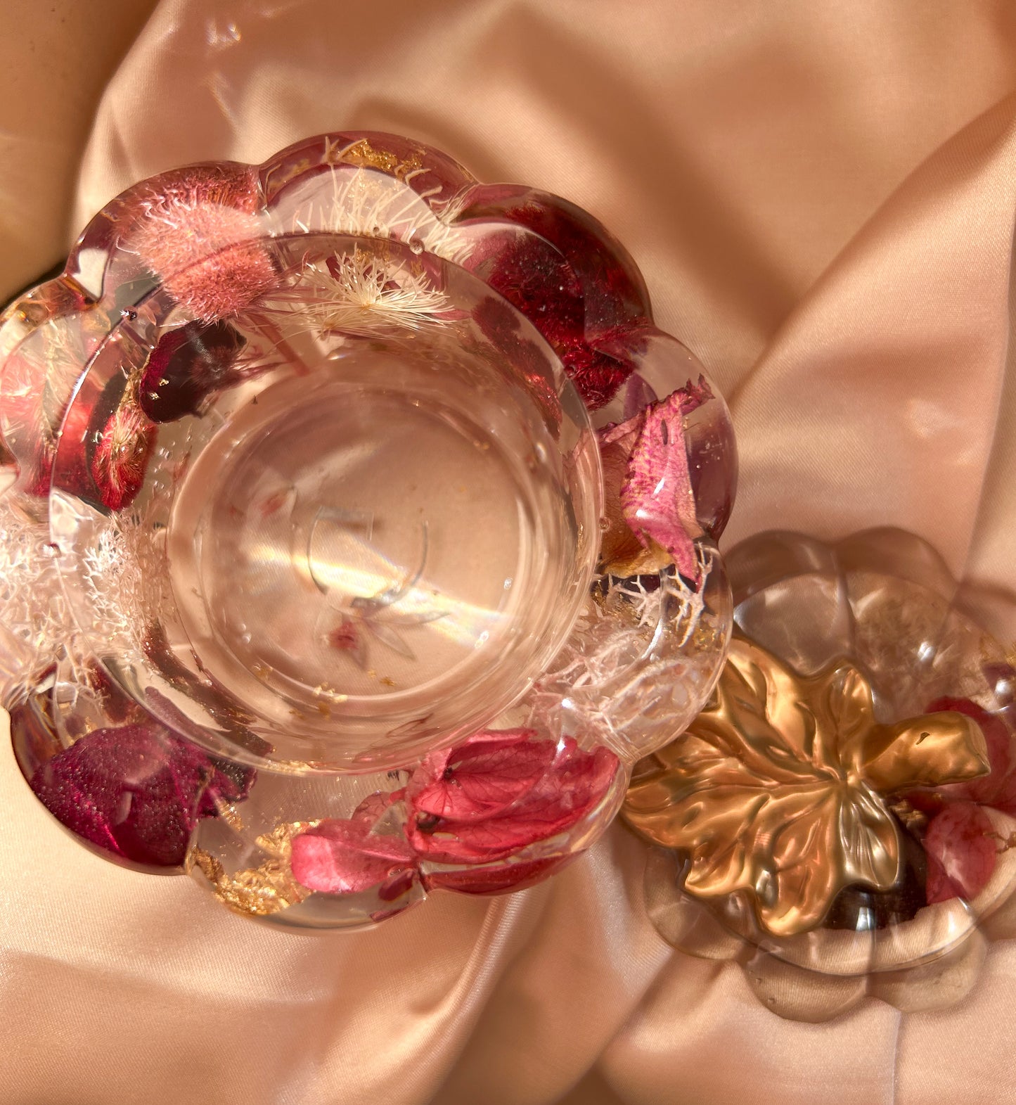 A handmade floral pumpkin-shaped resin jewelry jar with real dried flowers embedded inside. The jar has a smooth, glossy finish and is designed for storing rings, earrings, necklaces, and other small jewelry. Its elegant nature-inspired design makes it a unique decorative piece, perfect for boho or cottagecore home decor.
