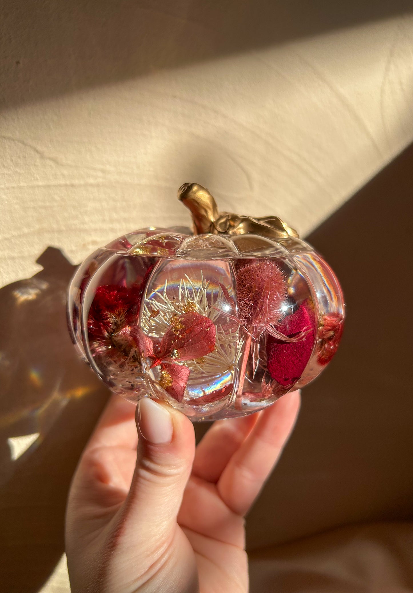 A handmade floral pumpkin-shaped resin jewelry jar with real dried flowers embedded inside. The jar has a smooth, glossy finish and is designed for storing rings, earrings, necklaces, and other small jewelry. Its elegant nature-inspired design makes it a unique decorative piece, perfect for boho or cottagecore home decor.
