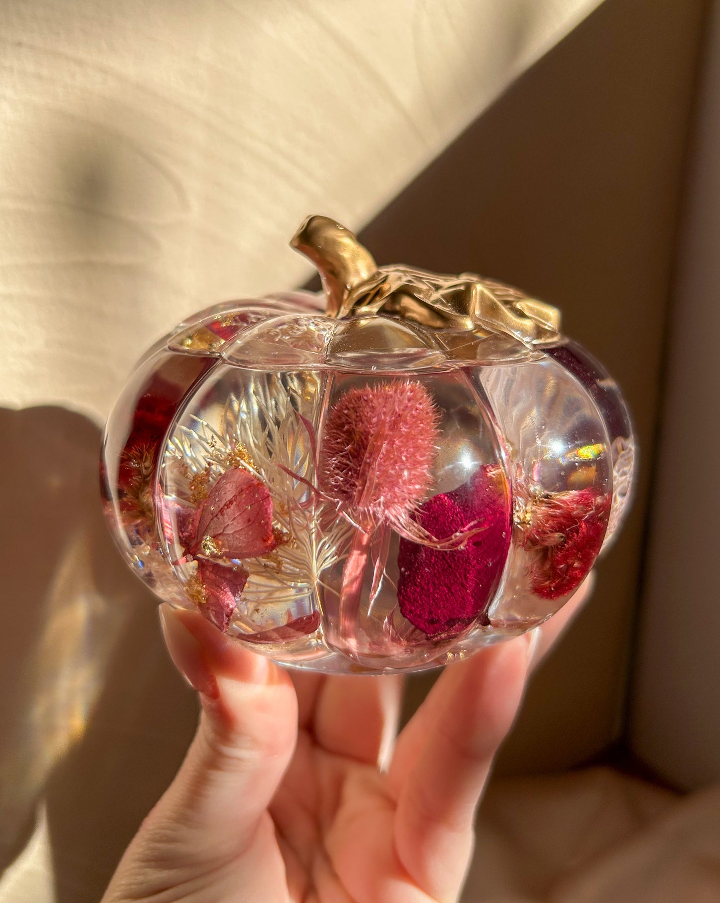 A handmade floral pumpkin-shaped resin jewelry jar with real dried flowers embedded inside. The jar has a smooth, glossy finish and is designed for storing rings, earrings, necklaces, and other small jewelry. Its elegant nature-inspired design makes it a unique decorative piece, perfect for boho or cottagecore home decor.