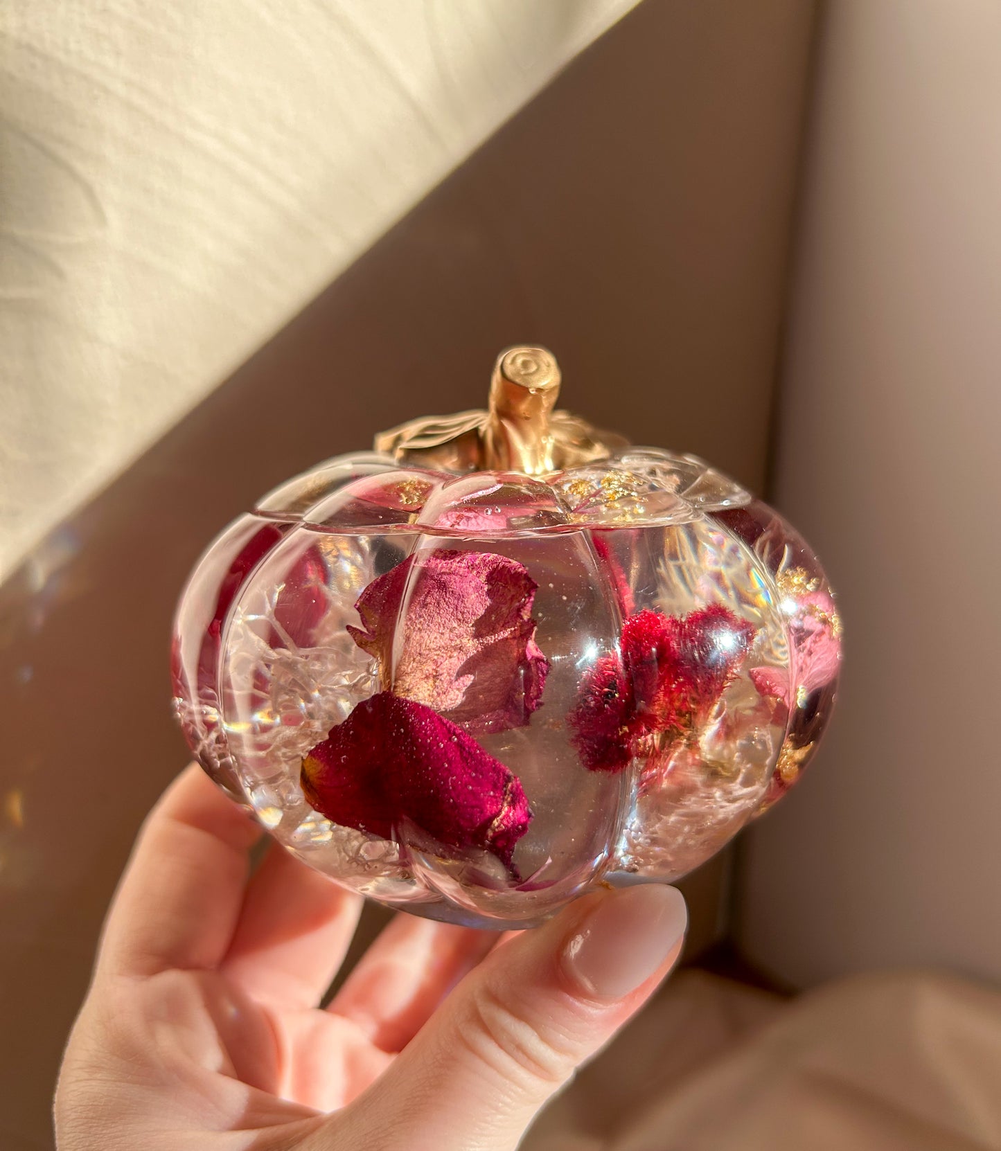 A handmade floral pumpkin-shaped resin jewelry jar with real dried flowers embedded inside. The jar has a smooth, glossy finish and is designed for storing rings, earrings, necklaces, and other small jewelry. Its elegant nature-inspired design makes it a unique decorative piece, perfect for boho or cottagecore home decor.
