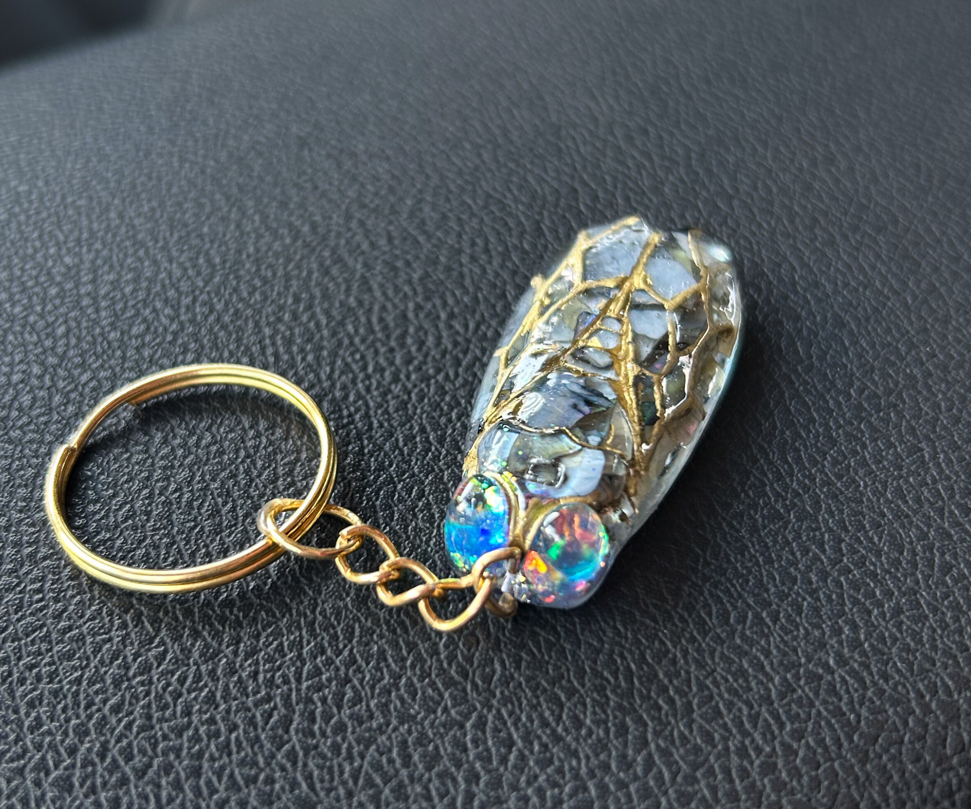 Handmade cicada keychain crafted with resin, real black abalone shell, glitter, and hand-painted ink, featuring a unique insect design, perfect for nature and bug lovers.