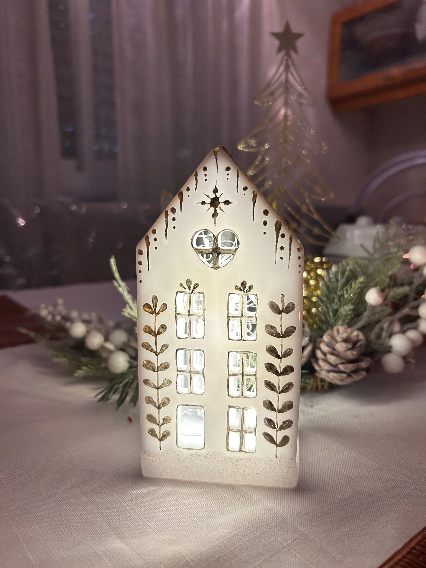 A beautiful handmade white resin gingerbread christmas tree house candle holder with golden decorations and a golden sparkly rooftop