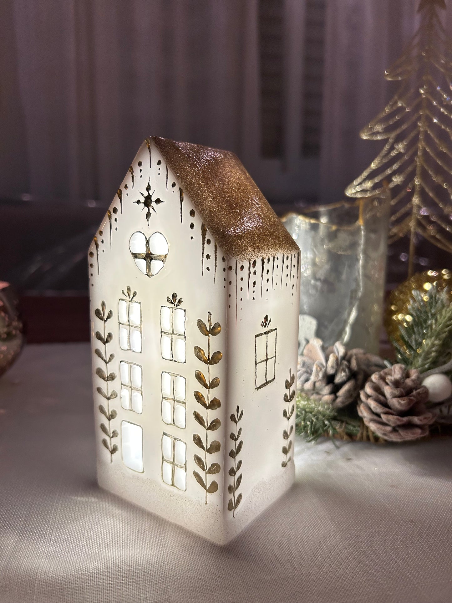 A beautiful handmade white resin gingerbread christmas tree house candle holder with golden decorations and a golden sparkly rooftop