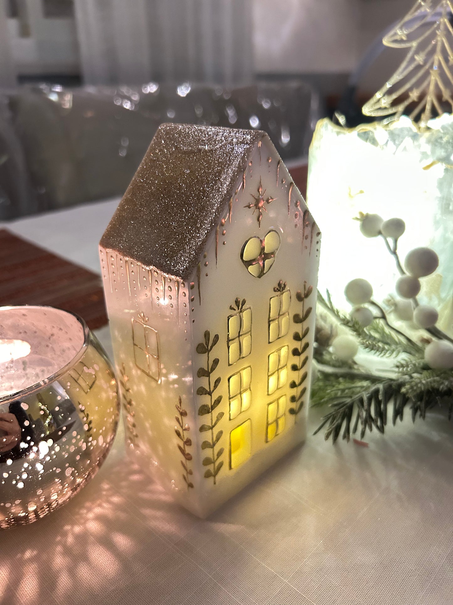 A beautiful handmade white resin gingerbread christmas tree house candle holder with golden decorations and a golden sparkly rooftop