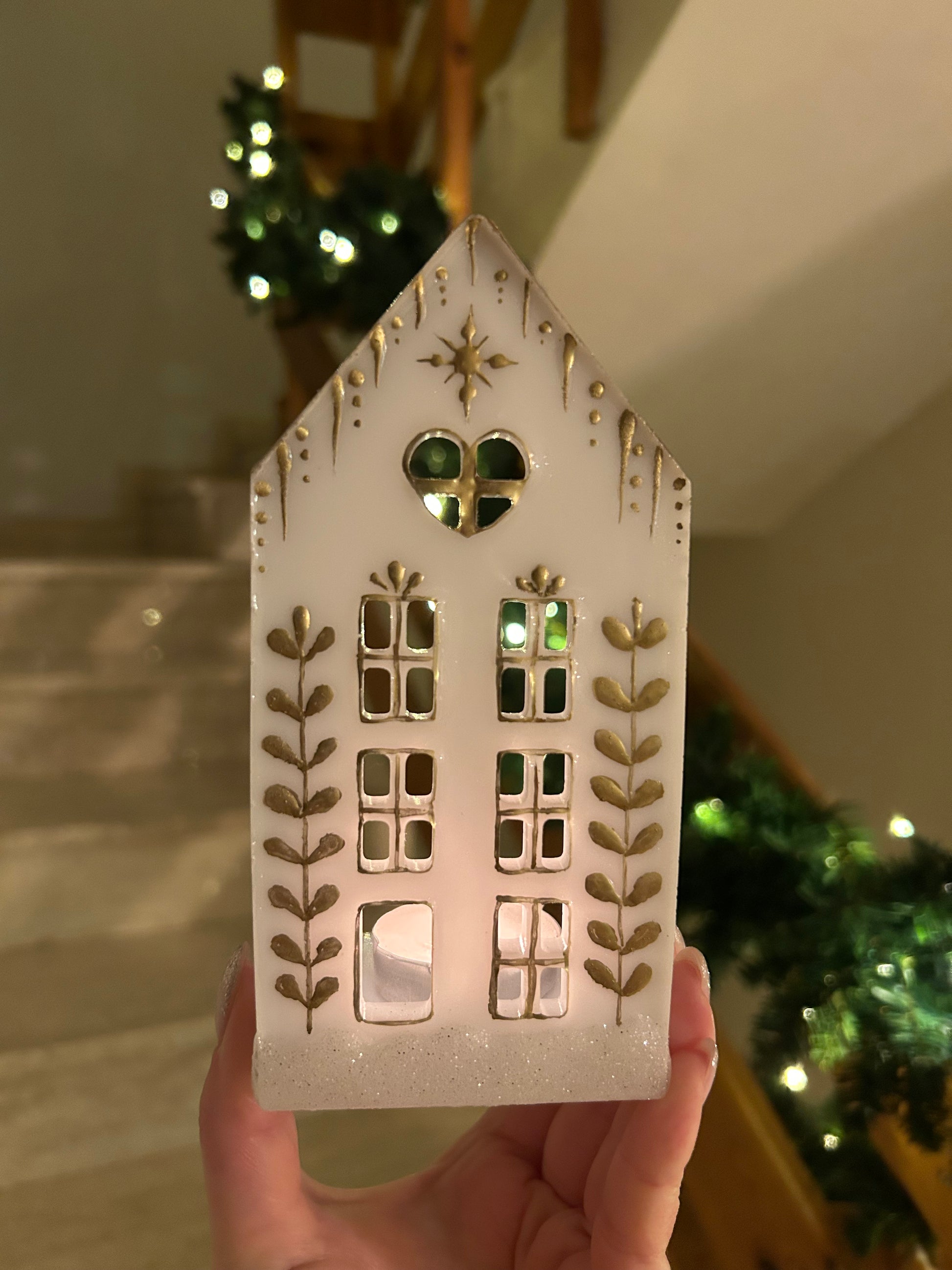 A beautiful handmade white resin gingerbread christmas tree house candle holder with golden decorations and a golden sparkly rooftop