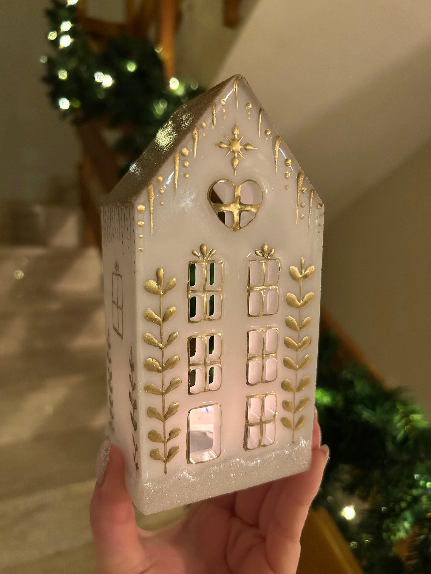 A beautiful handmade white resin gingerbread christmas tree house candle holder with golden decorations and a golden sparkly rooftop