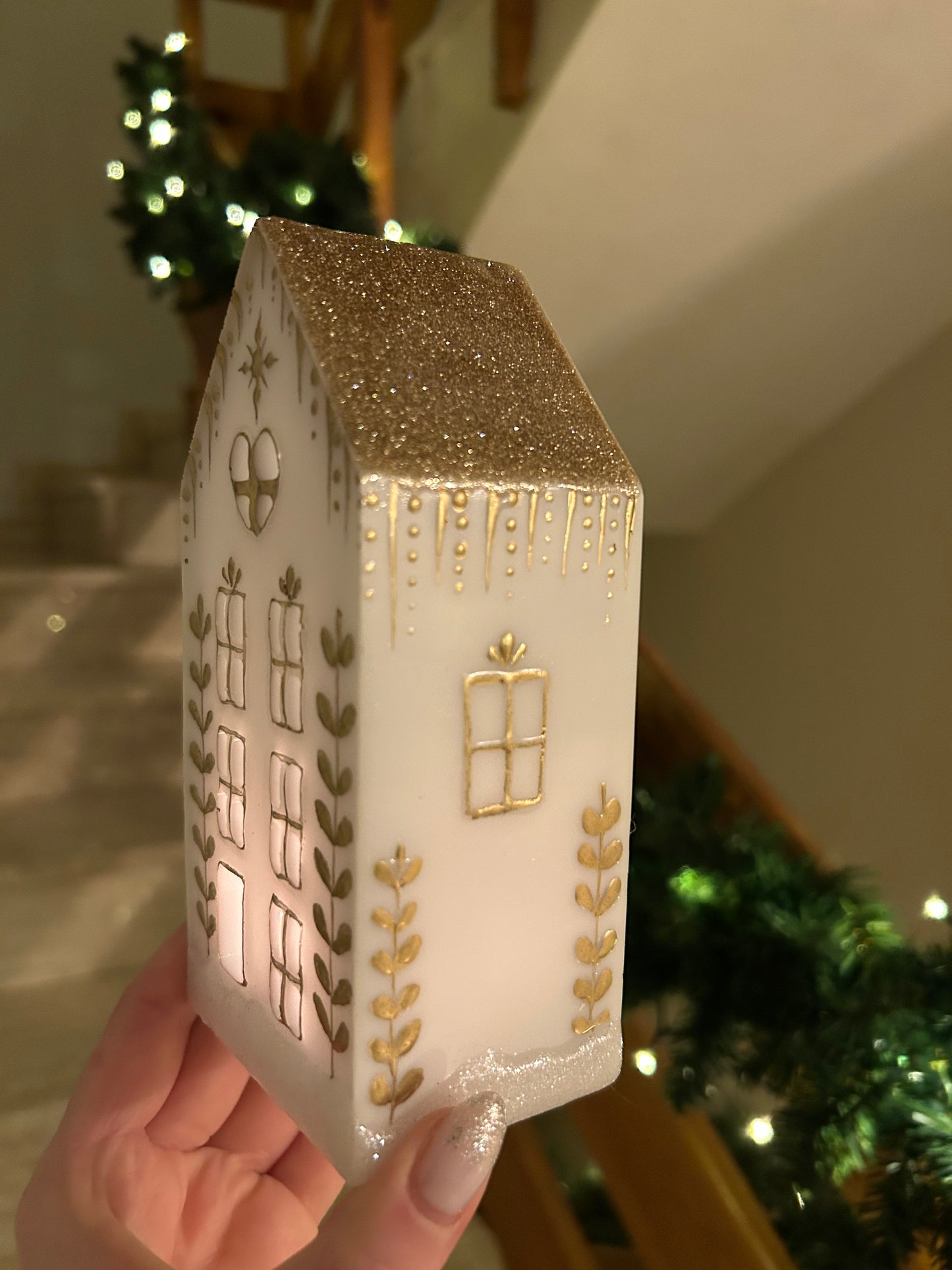 A beautiful handmade white resin gingerbread christmas tree house candle holder with golden decorations and a golden sparkly rooftop