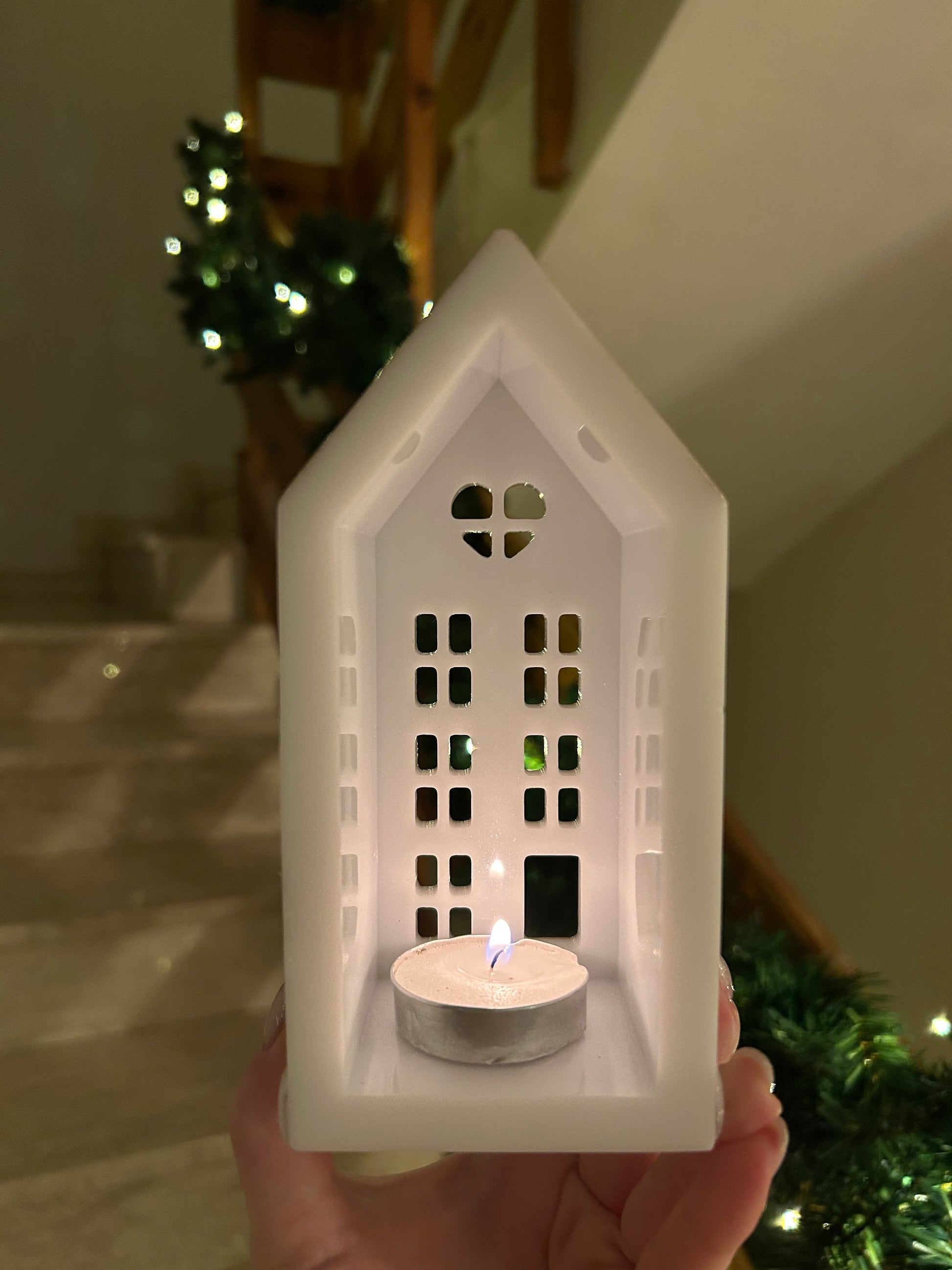 A beautiful handmade white resin gingerbread christmas tree house candle holder with golden decorations and a golden sparkly rooftop