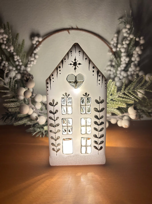 A beautiful handmade white resin gingerbread christmas tree house candle holder with golden decorations and a golden sparkly rooftop