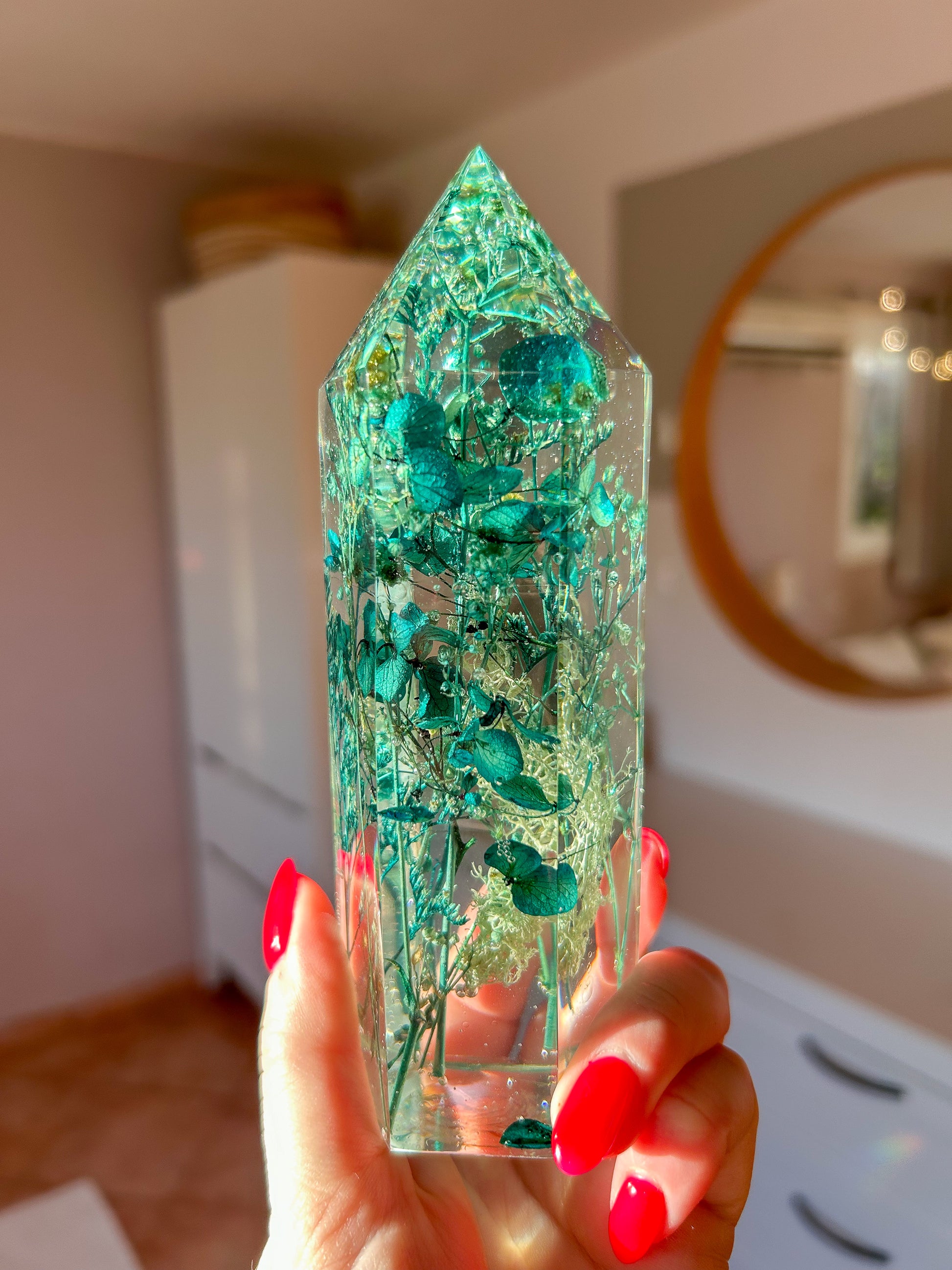 A beautiful handmade epoxy resin crystal made with blue teal, light blue and green natural dried flowers. perfectly cast in crystal clear epoxy resin. Great for home decor, gifts, unique presents, vanity bedroom decor and shelf decor.