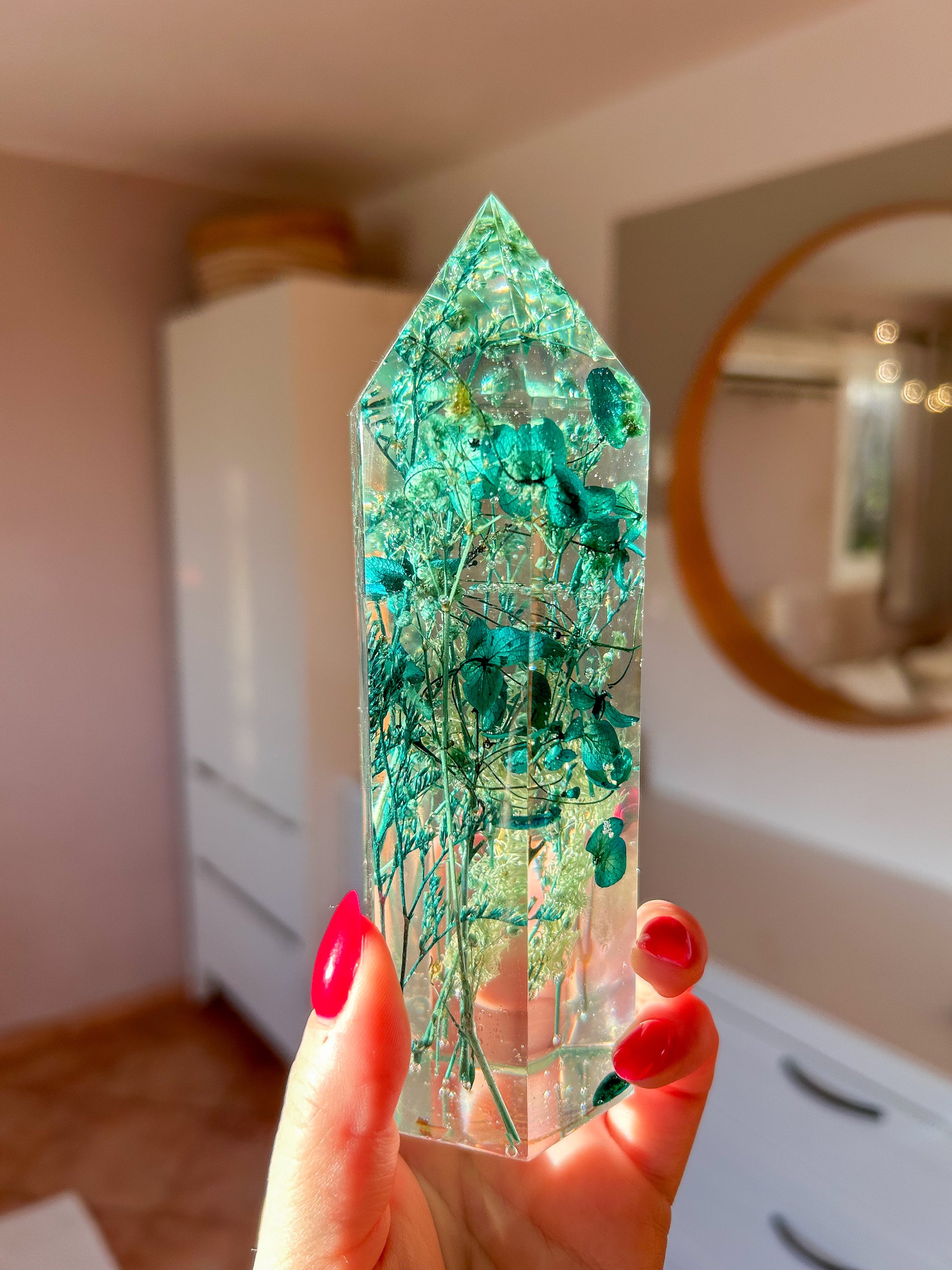 A beautiful handmade epoxy resin crystal made with blue teal, light blue and green natural dried flowers. perfectly cast in crystal clear epoxy resin. Great for home decor, gifts, unique presents, vanity bedroom decor and shelf decor.