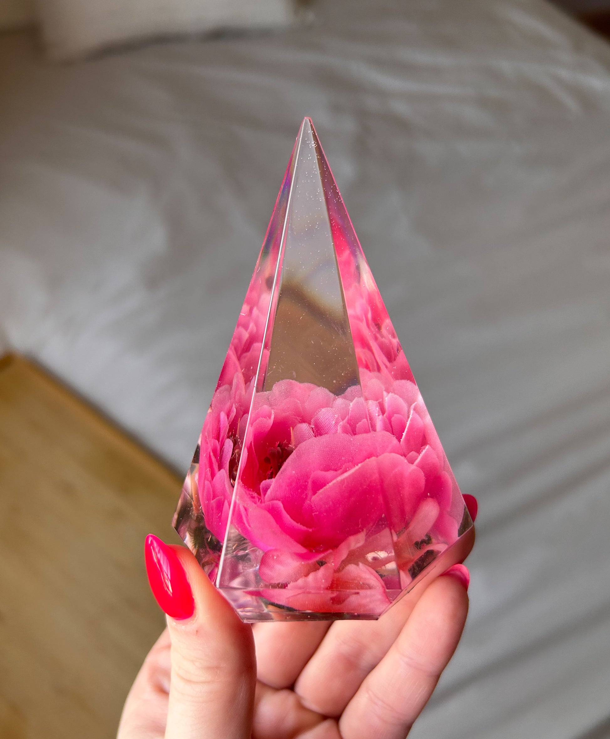 Handmade pink flower resin ring tree with real flowers encased in glossy resin. This jewelry holder is perfect for organizing rings and small accessories. Soft pink tones add a delicate touch, making it an ideal decorative piece or gift.