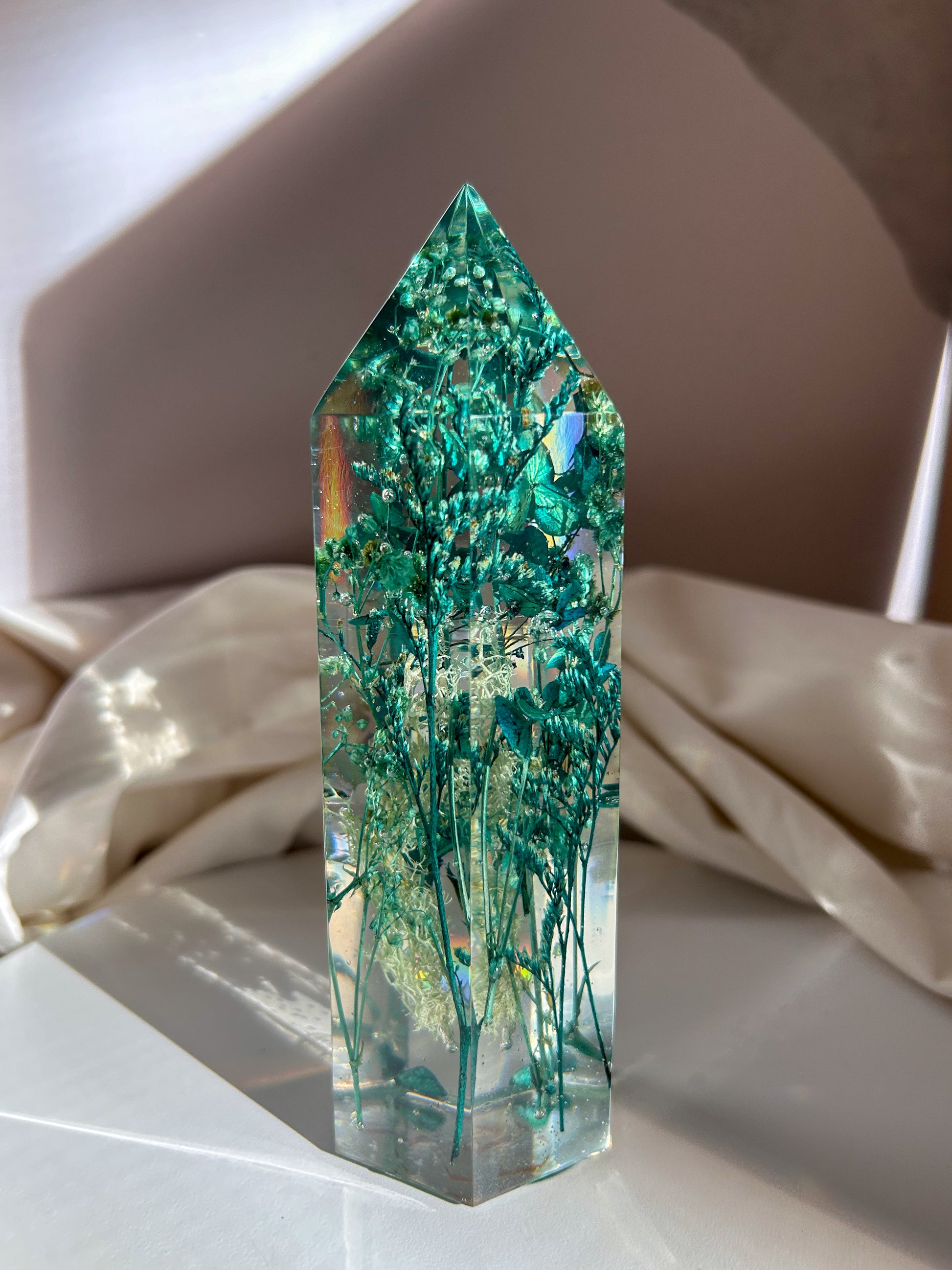 A beautiful handmade epoxy resin crystal made with blue teal, light blue and green natural dried flowers. perfectly cast in crystal clear epoxy resin. Great for home decor, gifts, unique presents, vanity bedroom decor and shelf decor.