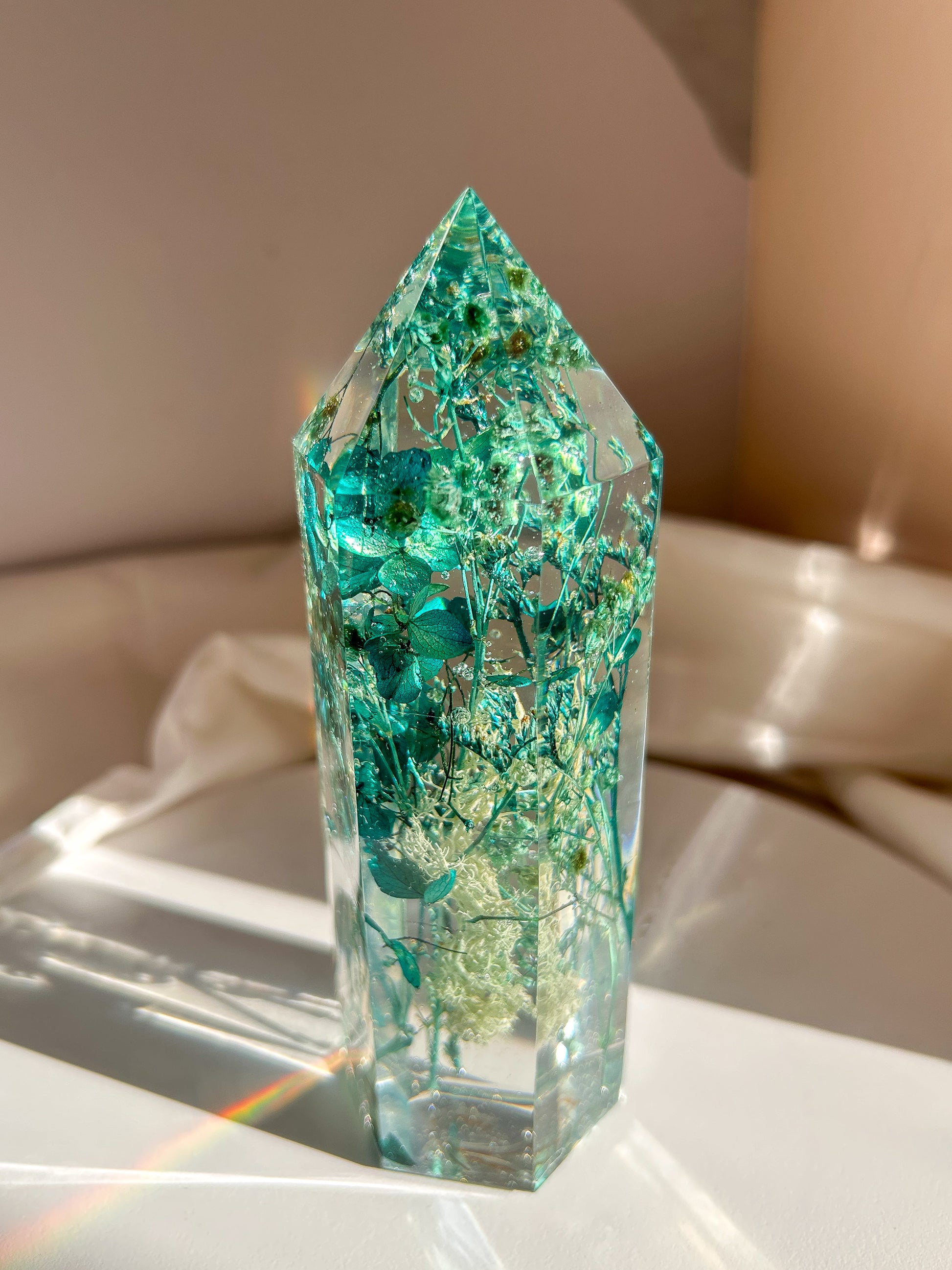 A beautiful handmade epoxy resin crystal made with blue teal, light blue and green natural dried flowers. perfectly cast in crystal clear epoxy resin. Great for home decor, gifts, unique presents, vanity bedroom decor and shelf decor.