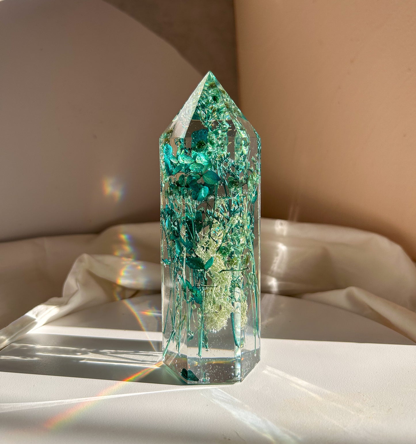 A beautiful handmade epoxy resin crystal made with blue teal, light blue and green natural dried flowers. perfectly cast in crystal clear epoxy resin. Great for home decor, gifts, unique presents, vanity bedroom decor and shelf decor.