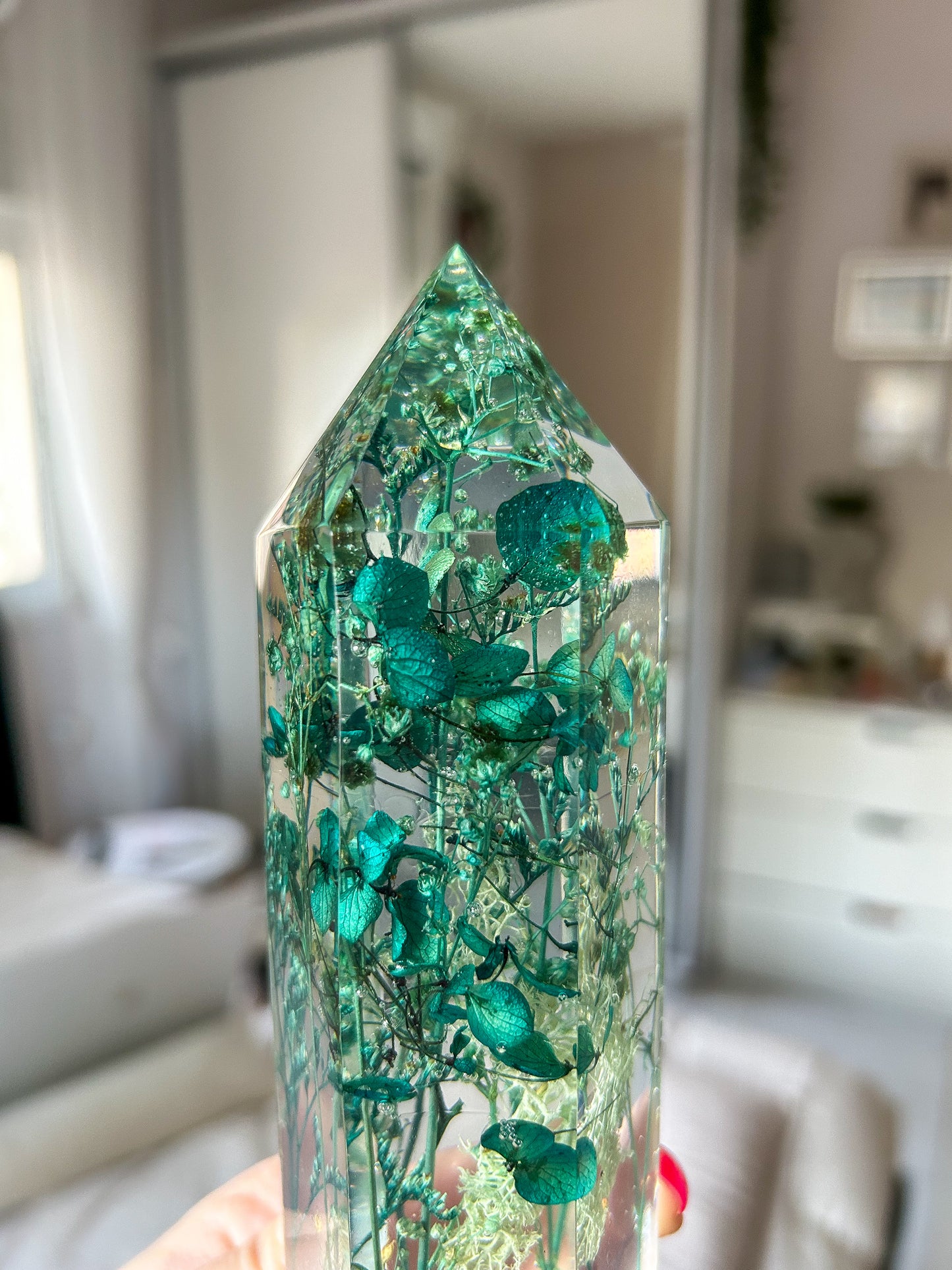 A beautiful handmade epoxy resin crystal made with blue teal, light blue and green natural dried flowers. perfectly cast in crystal clear epoxy resin. Great for home decor, gifts, unique presents, vanity bedroom decor and shelf decor.