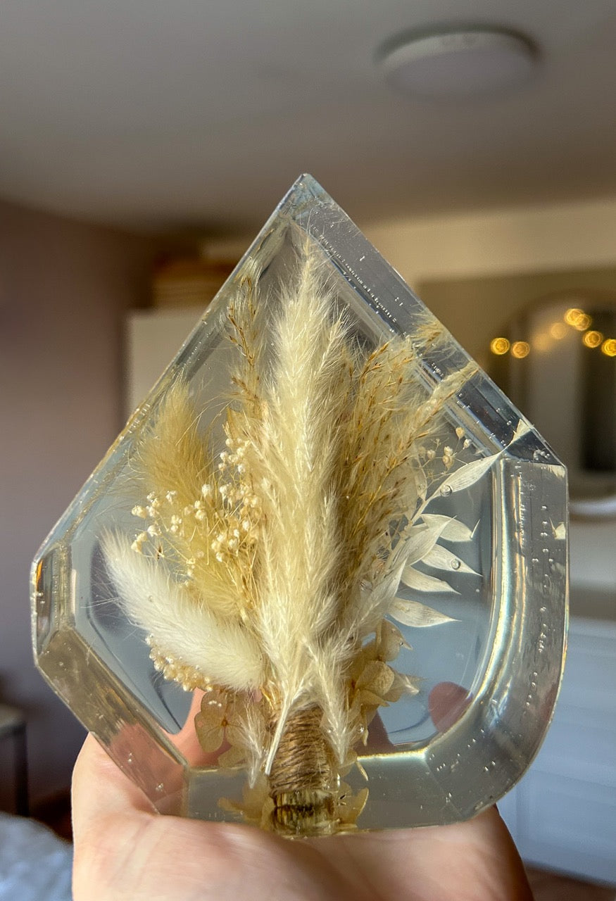 Gem-shaped resin decor featuring a preserved bouquet of dried flowers, including a striking burgundy red flower, all encased in clear resin. Handmade botanical art, perfect for unique home decor or as a thoughtful gift.