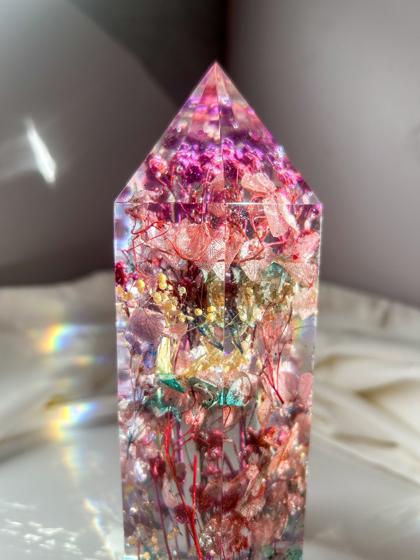 A beautiful crystal resin tower point with real dried flowers the colors of purple pink and a touch of blue beautifully decorates a bedside table and any room. great for gifting as a unique and handmade keepsake present.